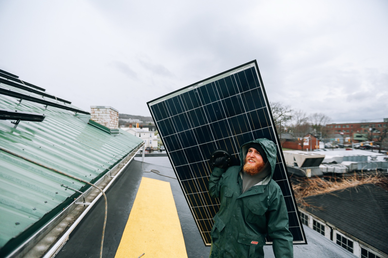 Techniker trägt ein Solarmodul über ein Hausdach